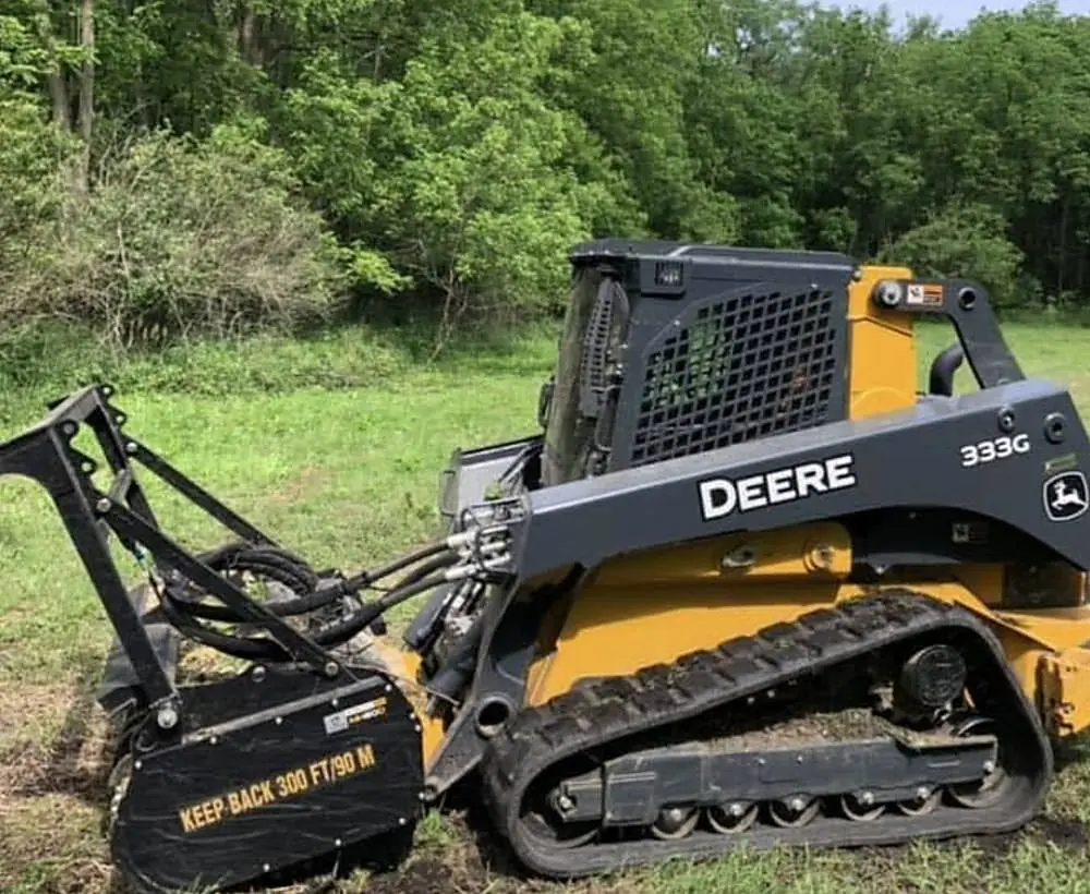 John Deere 333G tracked loader with forestry mulching head in a green field